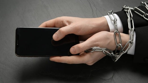 Chaîne de fer qui relie la main et le smartphone dans le concept de dépendance aux médias sociaux et à Internet