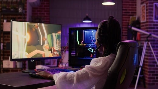 une gameuse utilisant une configuration de jeu sur PC s'amusant à jouer à un jeu d'action multijoueur en ligne