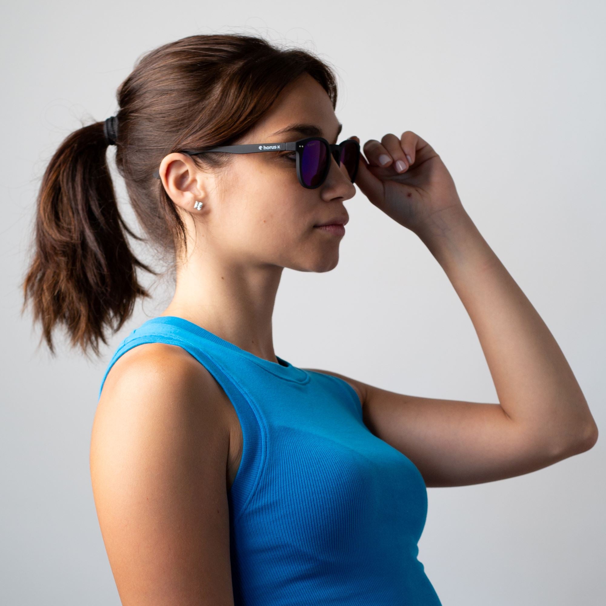 Rebecca porte nos lunettes de soleil sur fond gris, de profil